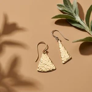 Gold hammered earrings on beige