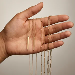 Layered gold necklaces in hand