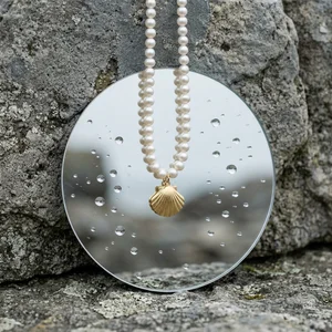 Pearl necklace on wet mirror and rock
