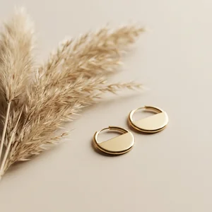 Minimalist gold earrings on beige