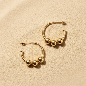 Gold earrings on rippled sand