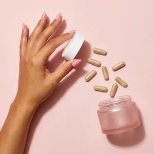 Pink flat-lay with capsules and hand