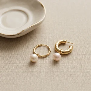 Gold pearl earrings on textured linen