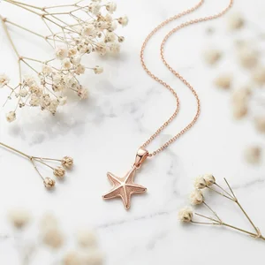 Rose gold starfish necklace on marble