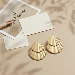 Gold shell earrings on beige paper