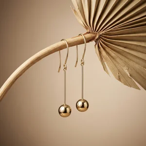 Gold ball earrings on dried palm
