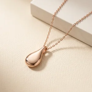 Rose gold teardrop necklace on textured paper