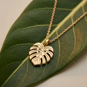 Gold monstera leaf necklace on leaf
