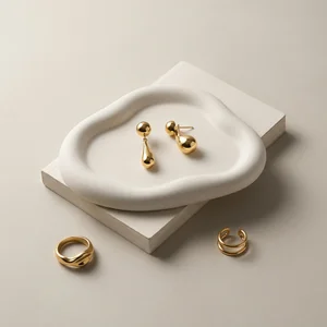Minimalist gold jewelry on ceramic tray