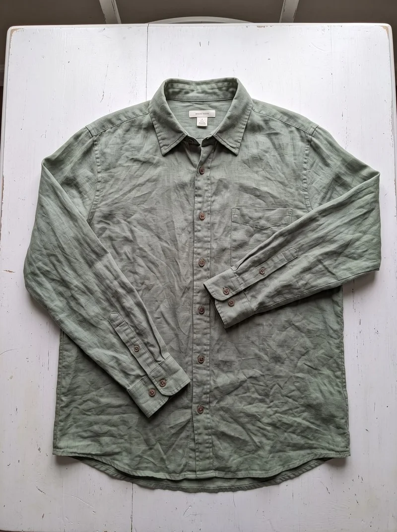 Flat-lay photo of a sage green linen shirt