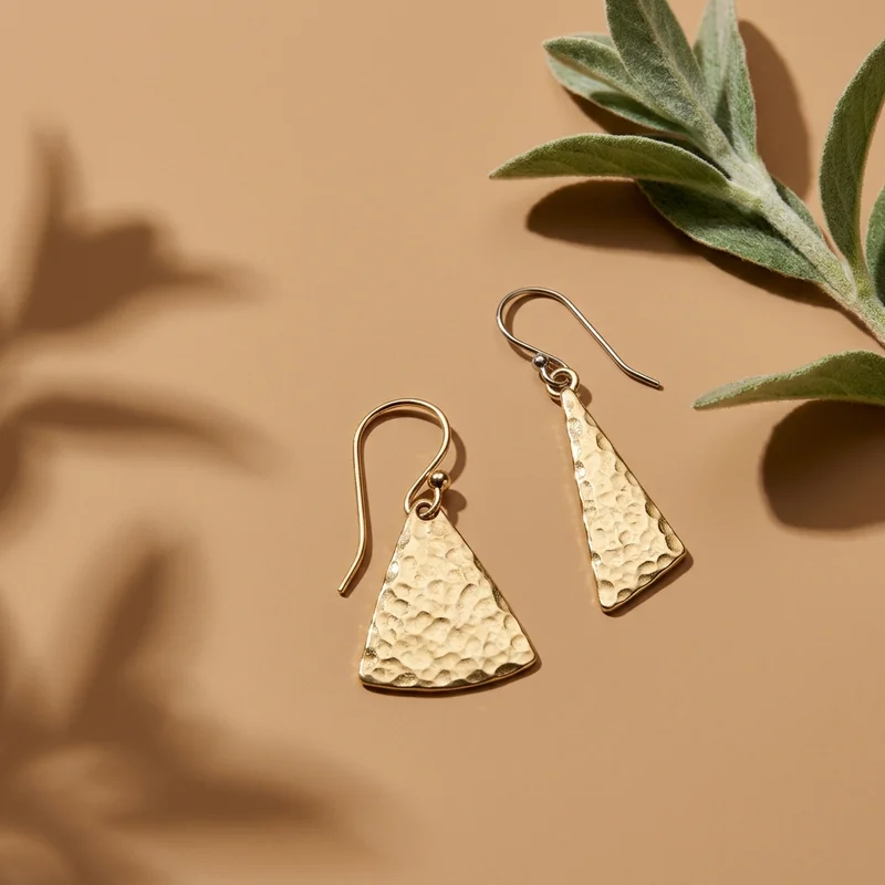 Gold hammered earrings on beige