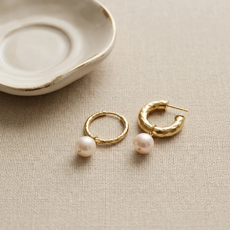 Gold pearl earrings on textured linen