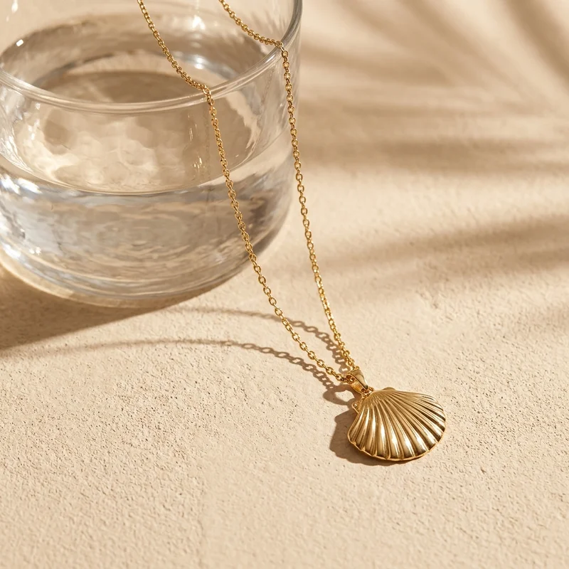 Gold seashell necklace on sand