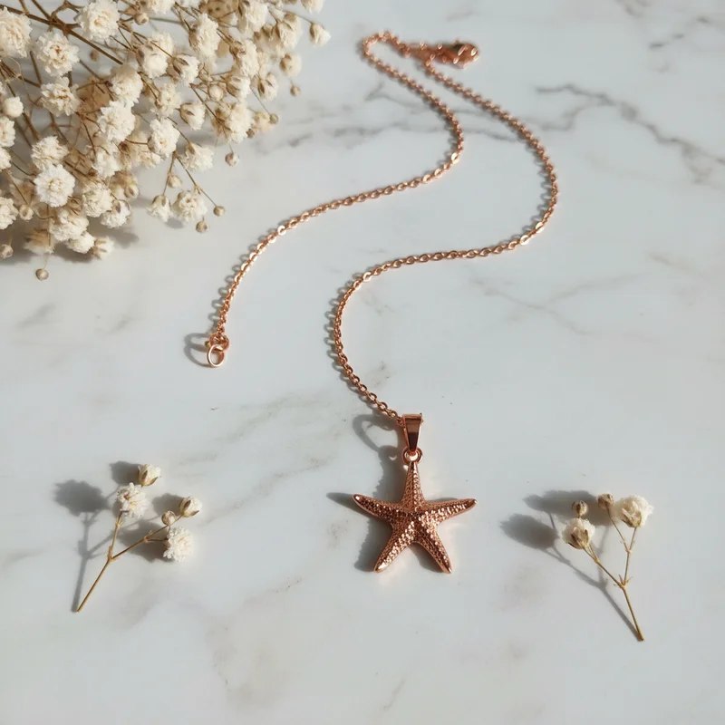 Star necklace on marble with flowers