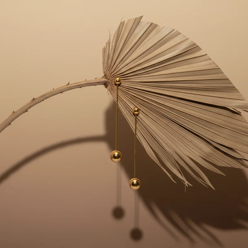 Gold earrings on dried palm leaf