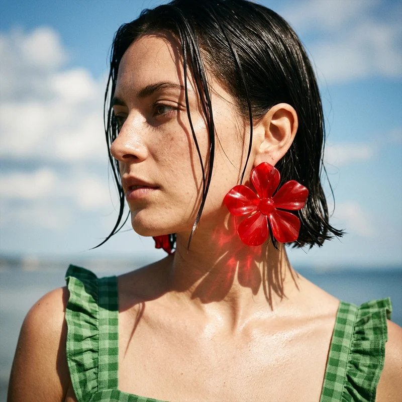 Bold red flower earrings on model