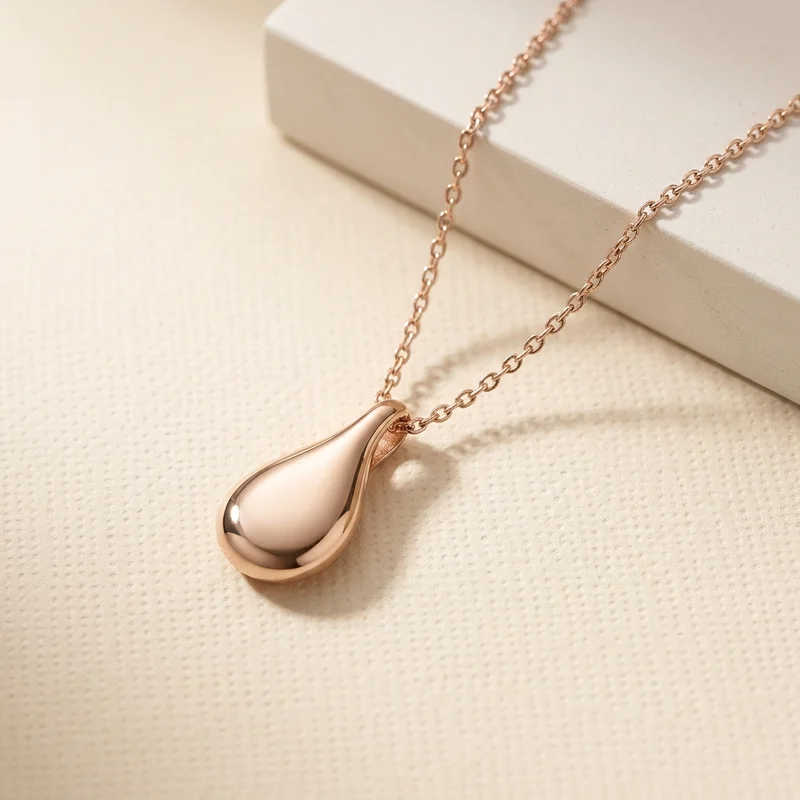 Rose gold teardrop necklace on textured paper