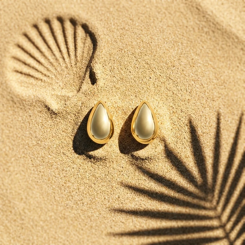 Gold earrings on beach sand